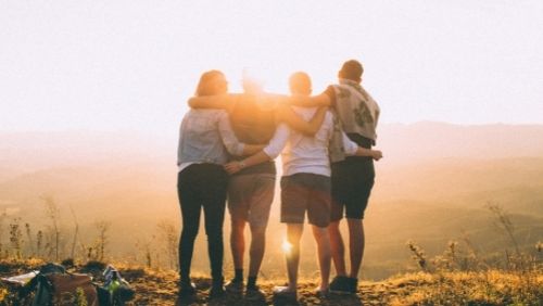 group of people arm in arm looking at sunset.