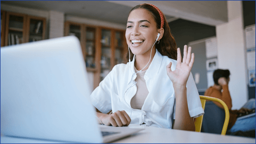 Woman smiling and waving at a laptop screen