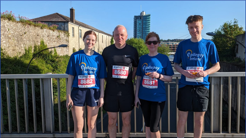 Group of four people standing on a bridge with medals around their necks