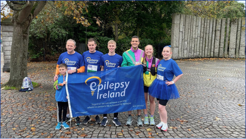Group of people in blue shirts standing behind an Epilepsy Ireland flag