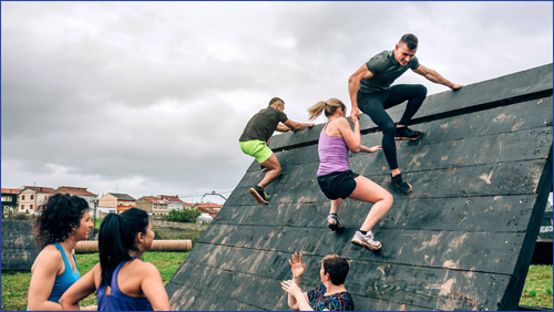 Man pulling a woman up over an obstacle course