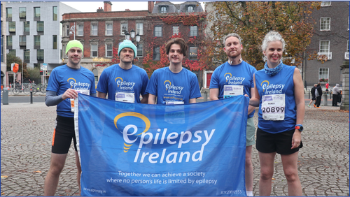 Five people in blue shirts around an Epilepsy Ireland flag