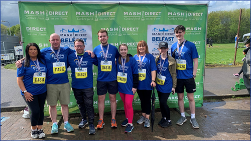Eight people wearing Epilepsy Ireland shirts standing in front of a green billboard