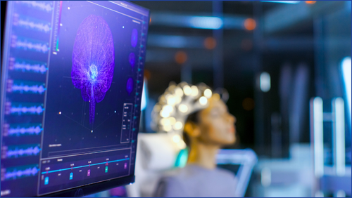 Person with brain electrodes on their head and screen showing images of their brain