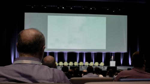A man sitting in front of a projector screen 