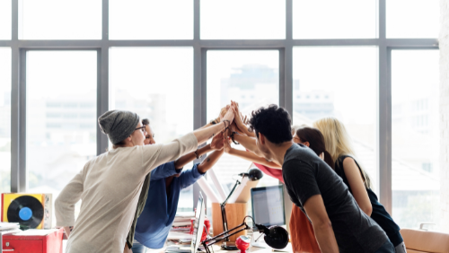 Group of people high-fiving in the workplace.