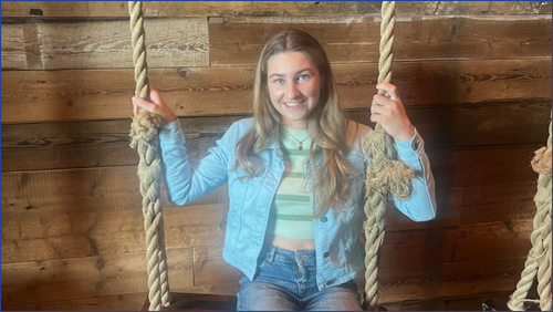 Girl sitting on a swing wearing a light blue jacket