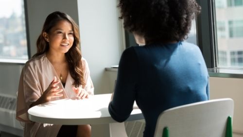 two women talking to eachother in a work setting.