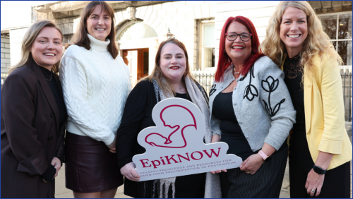 Women holding cut out of EpiKNOW logo 