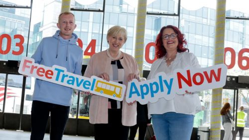 Wayne O'Reilly, Minister Heather Humphreys and Lisa Whelan holding placards in Bus Aras encouraging people to apply for Free Tracel