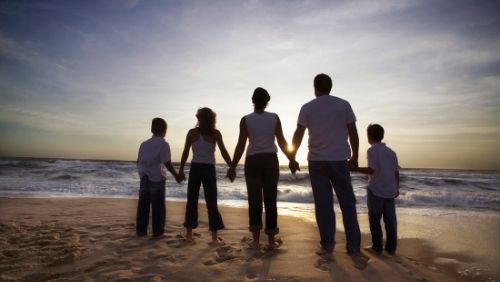 family holding hands looking at sunset.