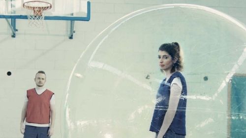 girl trapped in a zorb ball with a confused onlooker in the background.