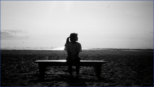 Girl sitting on bench at the beach
