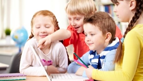 group of kids looking at a laptop.