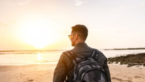 man on a beach looking at sunset.