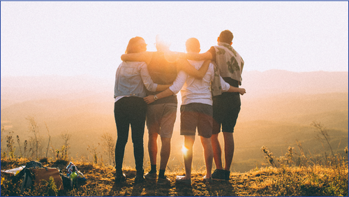 Four people hugging on a cliff in the sunshine