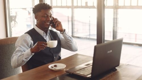 man looking at laptop and talking on phone.