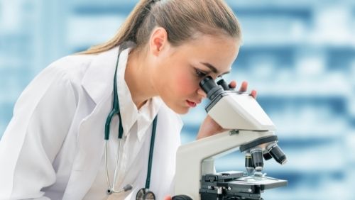 researcher looking through microscope. 