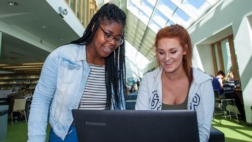 two students looking at a laptop