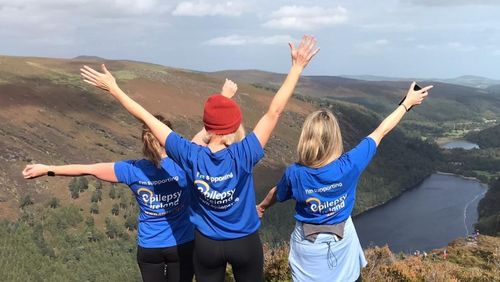 Three Epilepsy Ireland Volunteers celebrating reaching top of a mountain, overlooking a valley