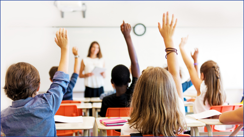 Children in the classroom raising their hand to answer a question.