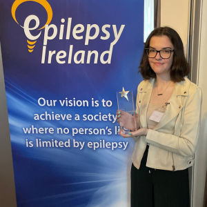 Melissa with her award standing in front of an EI Banner
