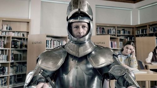 a person wearing suit of armour in a library. 