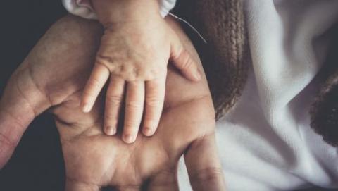 Baby's hand in a father's hand.