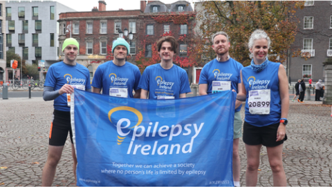 Five people in Epilepsy Ireland shirts holding an Epilepsy Ireland flag