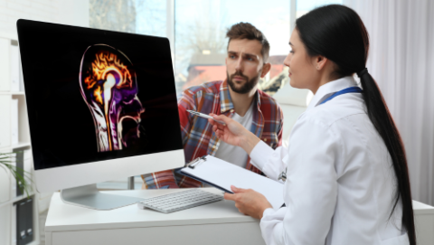Neurologist consulting with patient and image of brain on her display screen