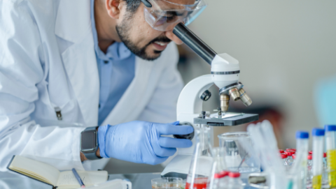 Researcher looking through microscope in the lab.