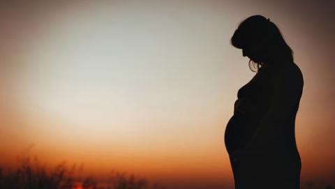 Pregnant person with sunrise in background.