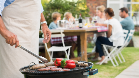 Man BBQing with people sitting in background